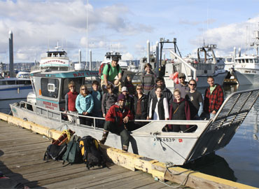 A group of students aboard a water taxi prepare for a beach cleanup