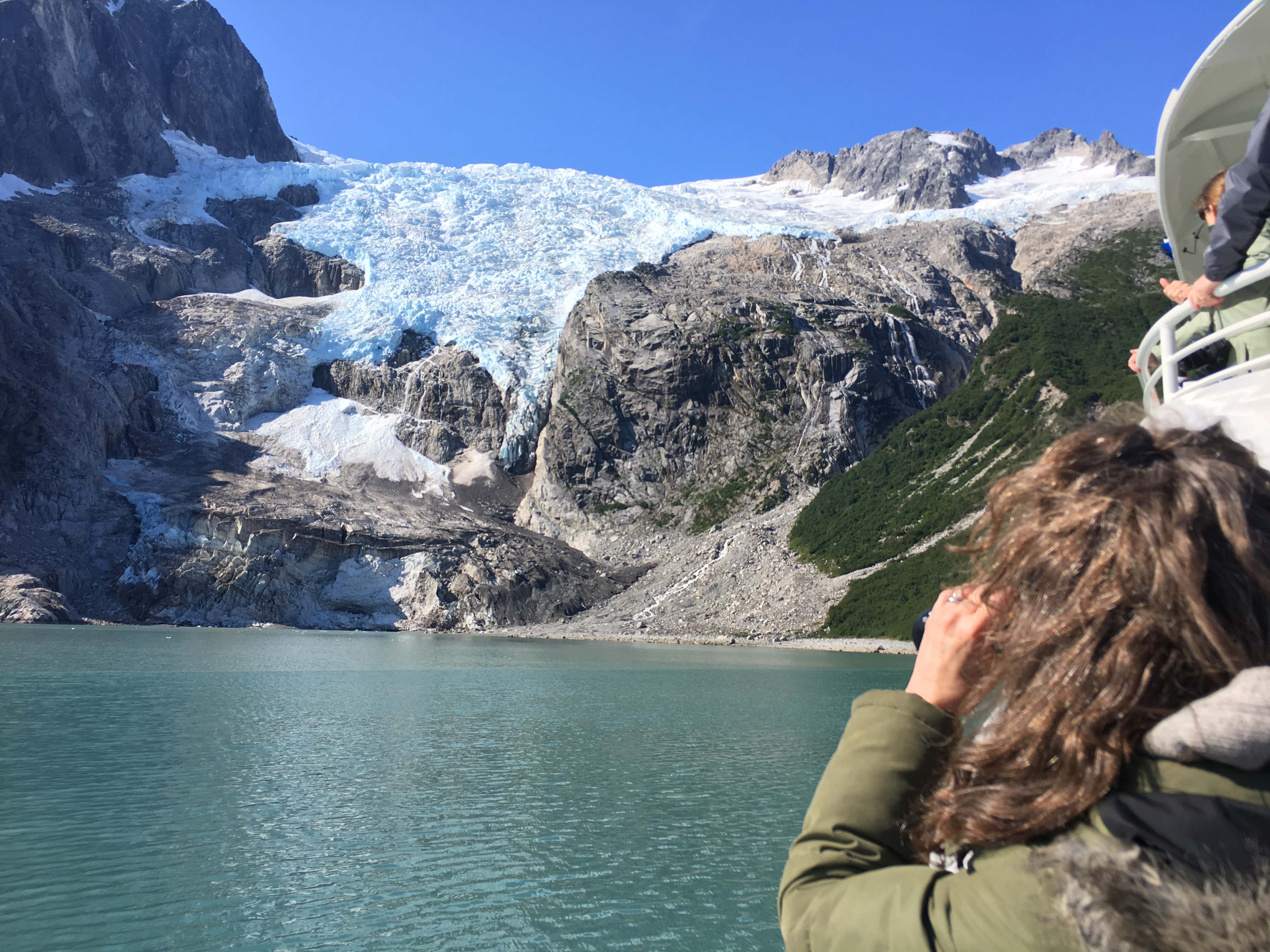 A student looks through binoculars at a looming blue glacier